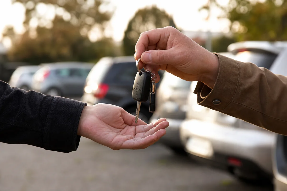 Remise de clés de voiture entre deux personnes sur un parking